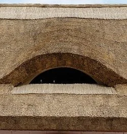 Detail doškové střechy s obloukovým otvorem v přízemí.