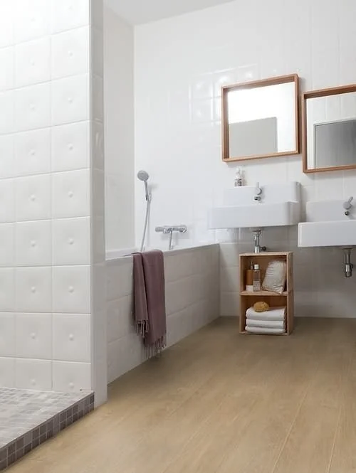 Moderní koupelna s dřevěnou podlahou a bílými dlaždicemi.