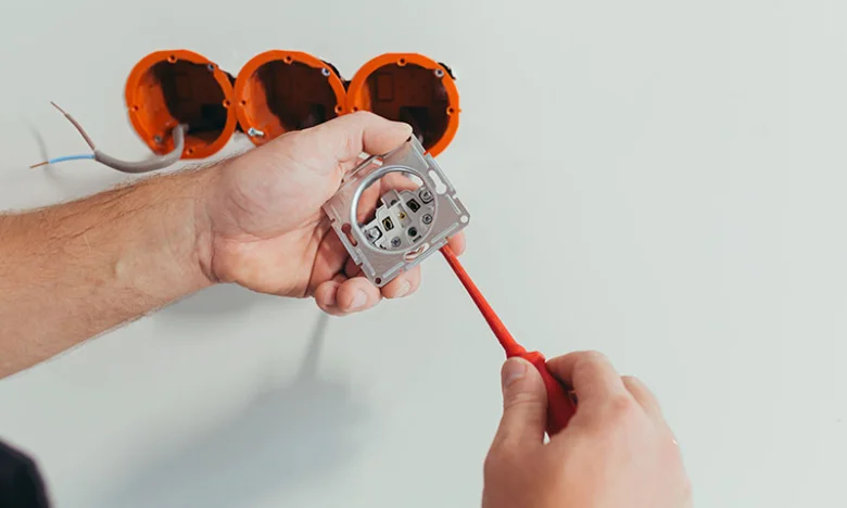 Instalace elektrického zásuvky do zdi s viditelnými vodiči.