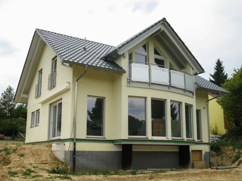 Dům s žlutou fasádou v procesu malování.