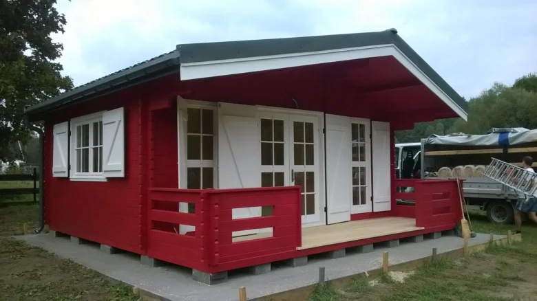 Červená dřevěná přístavba domu na základové desce.