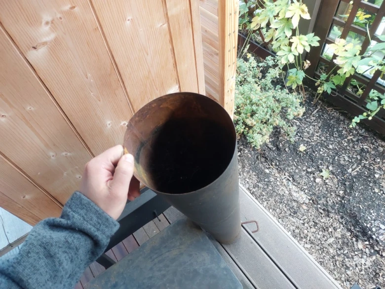 Ruční instalace kovového komínového vložku do zděné udírny.