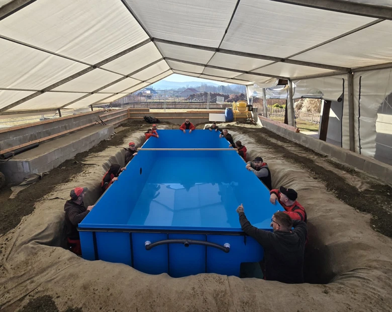 Práce na instalaci modrého bazénu do země pod střešním plachtovým stanem.