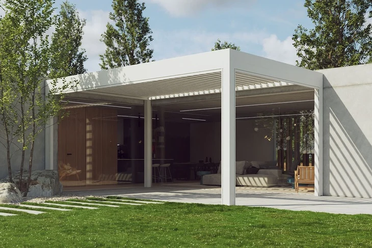 Moderní bílá bioklimatická pergola s proskleným interiérem v zeleném prostředí.