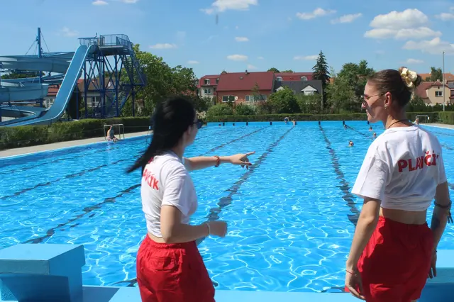 Dva záchranní pracovníci u bazénu v Dubňanech ukazují na plavce.
