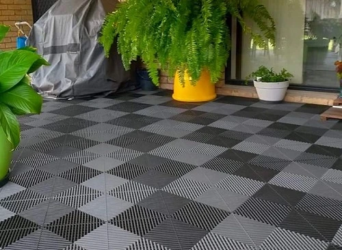 Sedací podlaha z propojených dlaždic na balkóně s rostlinami.