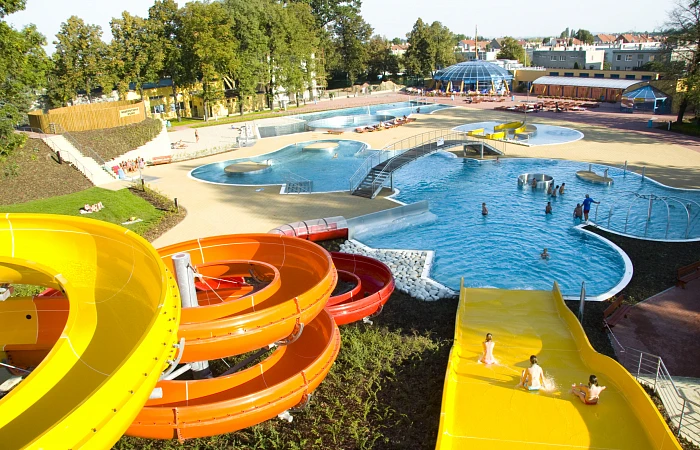 Venkovní aquapark s barevnými skluzavkami a bazény.