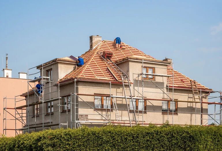 Stavebníci rekonstruují střechu domu na provizorním schodišti.