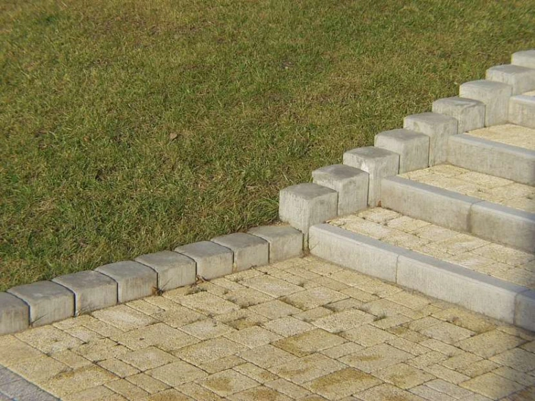Hotová schodiště z dlažby s obrubníkem vedle trávníku.