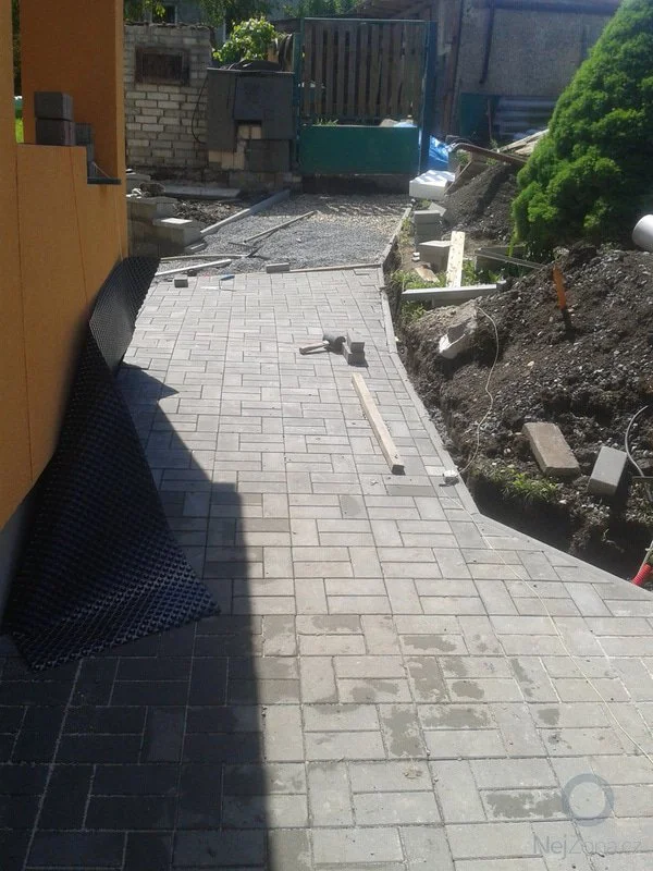 Pokládka zámkové dlažby na zahradě s nástroji.