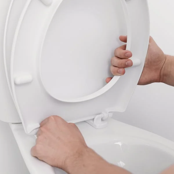 Ruční instalace bílého prkénka na toaletu