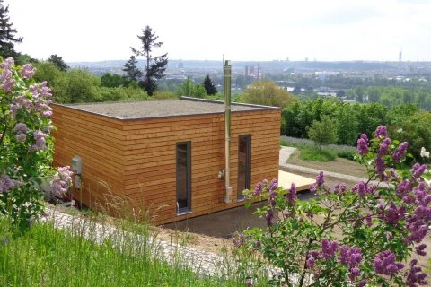 Moderní dřevěný zahradní domek na svahu s výhledem do kraje.