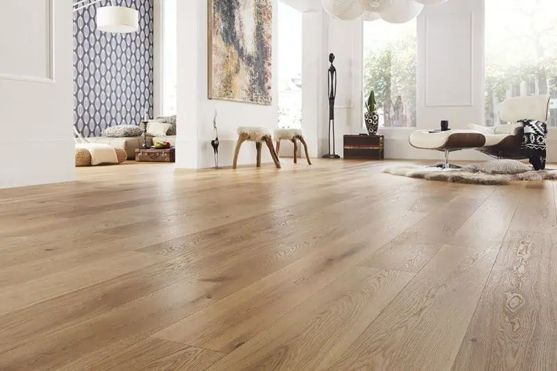 Moderní dřevěná podlaha v obývacím pokoji s minimalistickým nábytkem.