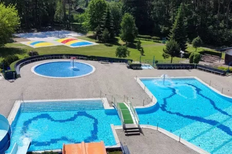 Vnější bazénový komplex s více plaveckými bassény v zeleném parku.