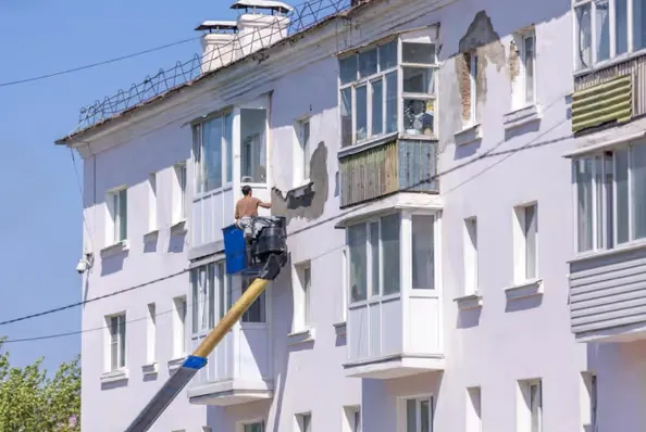Stavebník opravuje fasádu lodžie v bytovém domě.