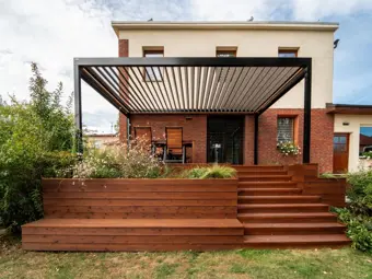 Bioklimatická pergola s dřevěnou terasou u domu.