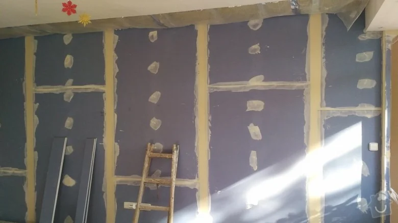 Instalace sádrokartonu na dřevěné trámy v interiéru.