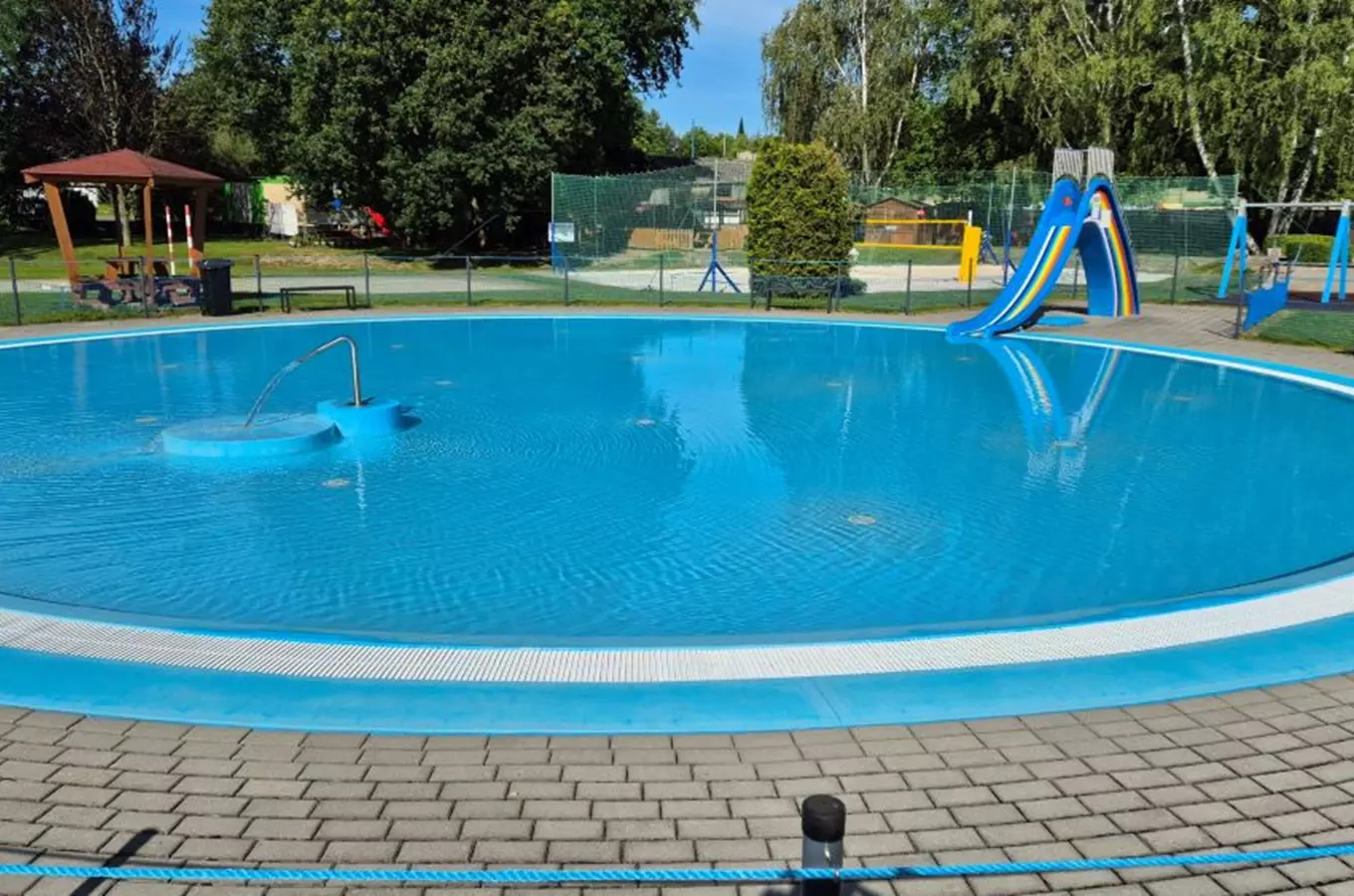 Venkovní bazén ve Vlašimi s dětskou skluzavkou.