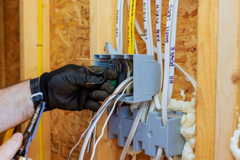 Ruční instalace elektrického vedení v rozvaděči během rekonstrukce bytu