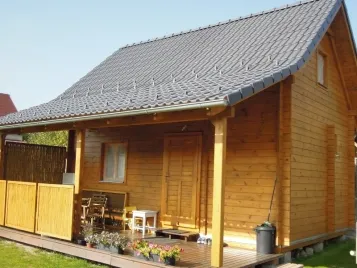 Drevená chata s terasou a zahradním nábytkem.