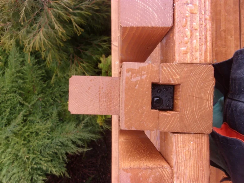 Detail dřevěného spojení na balkonu s přírodním pozadím.