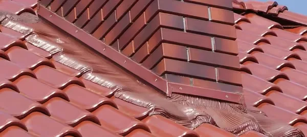 Červené střešní tašky s hydroizolační fólií kolem komína.