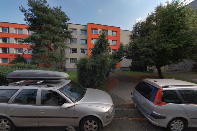 Stříbrné vozy před oranžovým domem s okolním zeleň.
