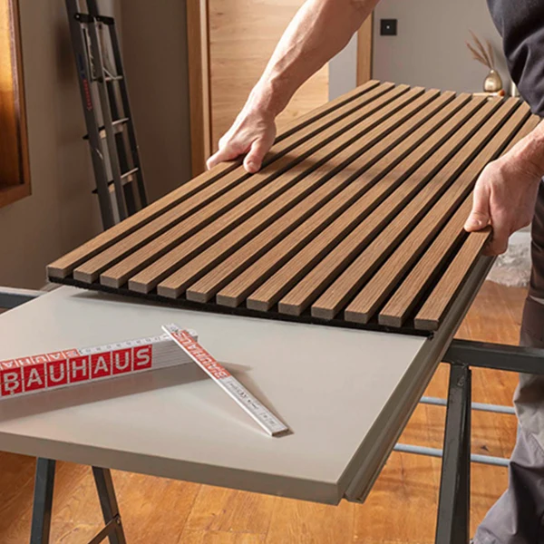 Instalace dřevěných akustických panelů na stěnu pro zvukovou izolaci.