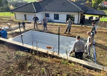 Stavba venkovního bazénu s pomocí pracovníků u domu.
