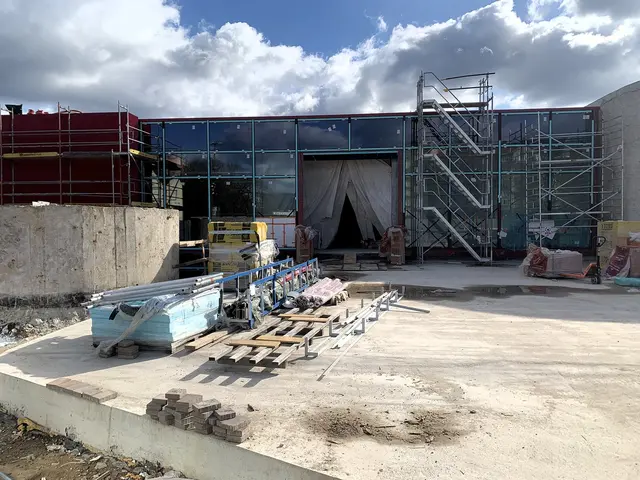 Staveniště plaveckého bazénu s konstrukcí z skla a lešení.
