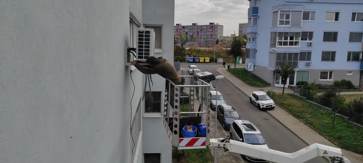 Technik opravuje klimatizační jednotku na budově v Brně.
