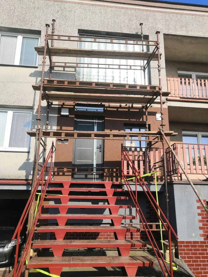 Skelet pro instalaci sítí do oken na fasádě bytového domu.