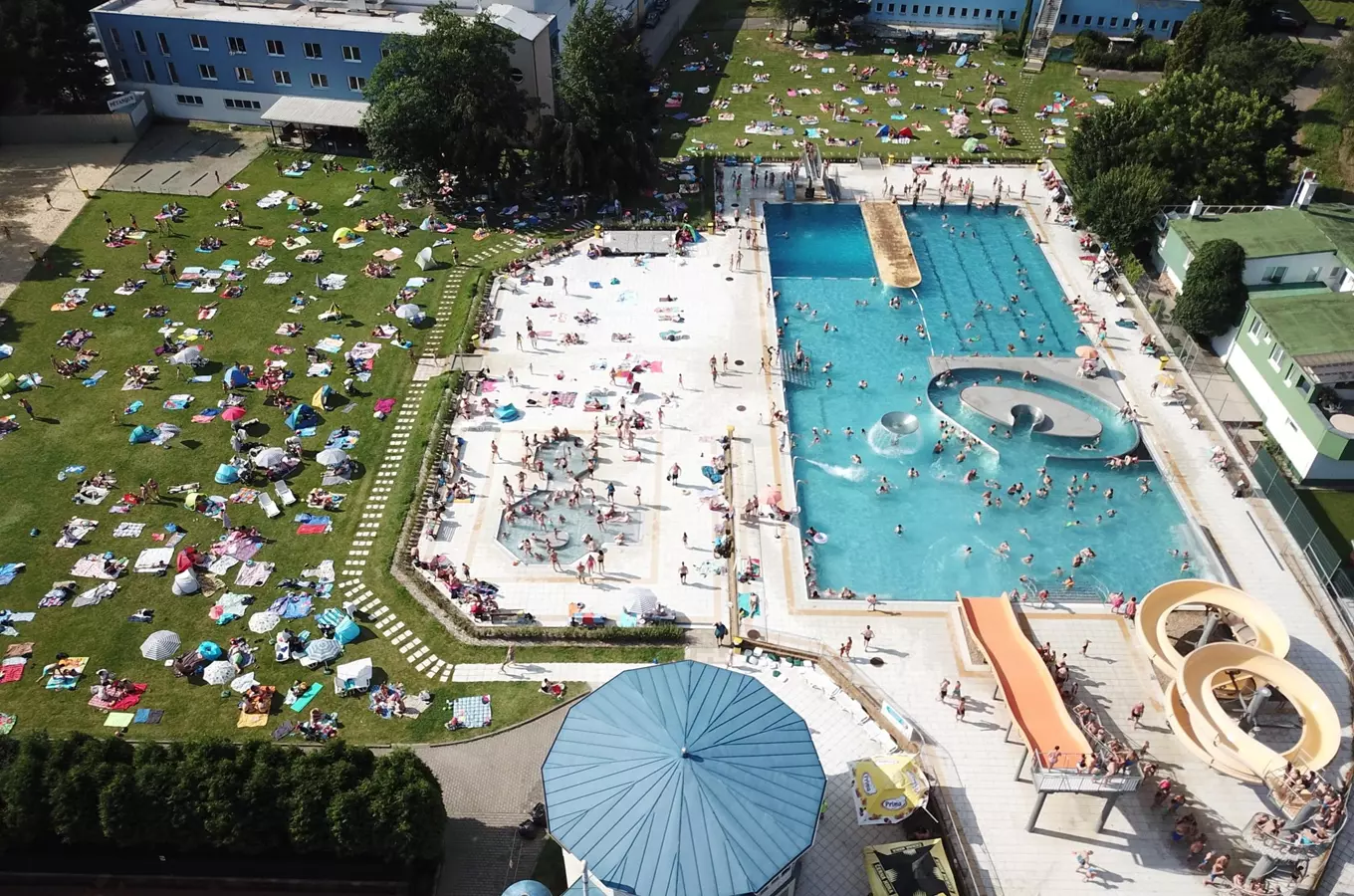 Pohled z výšky na aquapark Blansko s bazénymi a lehátky.