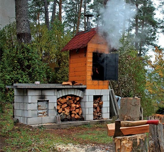 Zděná udírna s dřevem v lese