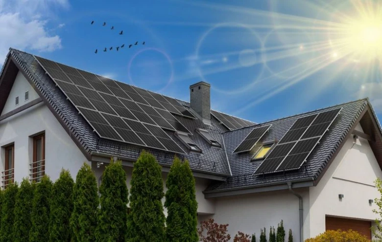 Dům s fotovoltaickými panely na střechě pod sluncem.