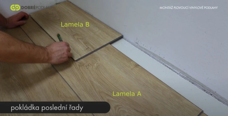 Muž pokládá vinylovou podlahu s označením lamel.