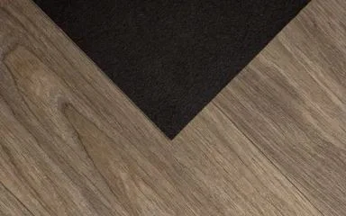Kout tmavého koberce na dřevěné podlaze