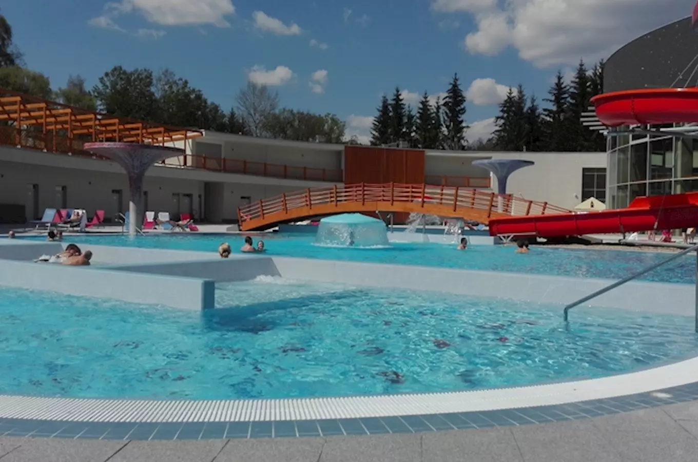 Venkovní bazén s vodními skluzavkami v aquaparku na Moravě.