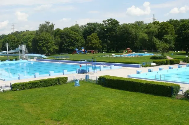 Venkovní bazény s vodními skluzavkami a hřištěm pro děti.