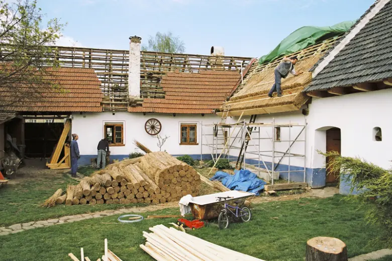 Práce na doškové střechě s trávy a slámou.