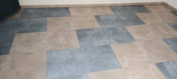 Pohled na dlažbu v koupelně s béžovými a šedobílými obdélníkovými dílky.