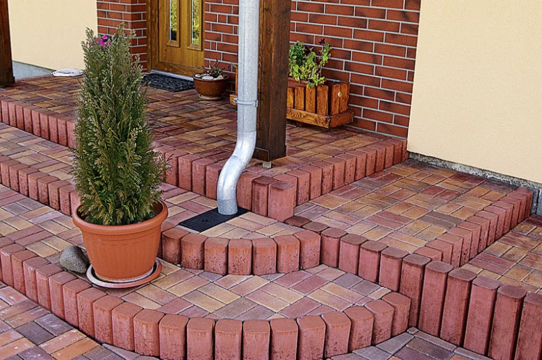 Zpevněný svah červenými cihlovými palisádami s kvetináčemi.