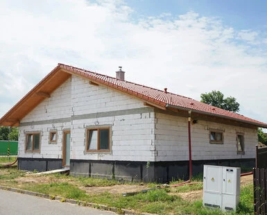 Rodinný dům z vápenopískových tvárnic s červenou střechou.
