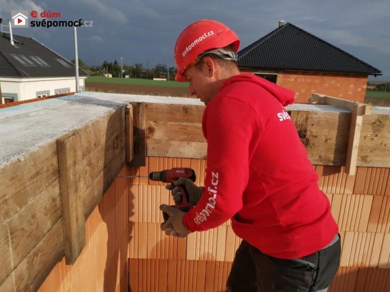Stavebník upevňuje bednění pro betonový věnci na stavbě.