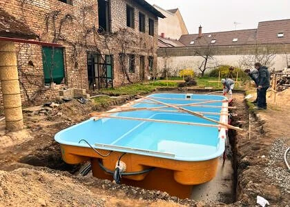 Modrý nadzemní bazén se instaluje do vykopaného jámy vedle domu.