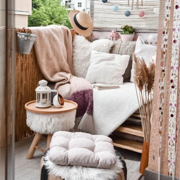 Uspořádaný balkon s měkkým nábytkem a dřevěnou podlahou.