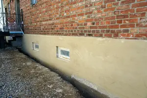 Vápenná omítka na spodní části zdiva domu venku.