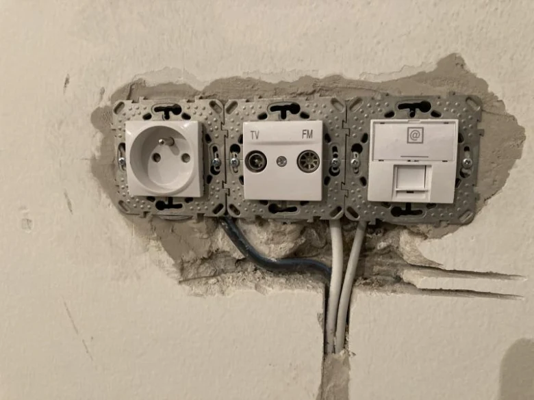 Instalace elektrických zásuvek v zdi během rekonstrukce bytu.