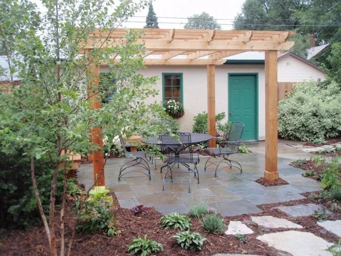 Dokončená dřevěná pergola na zahradě s venkovním nábytkem.