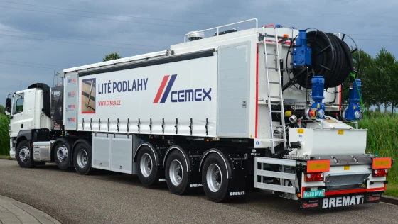 Bílá nákladní betonová smíchávka značky CEMEX na silnici.